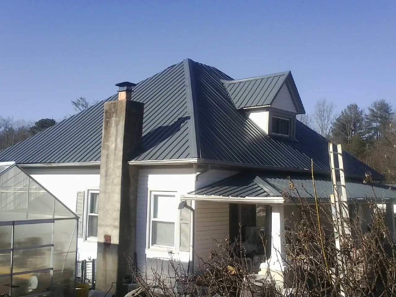 Dark blue standing seam metal roof on a white farmhouse with dormer — Slate & Tile Roof Repair by Roofing Brothers in Rockbridge
