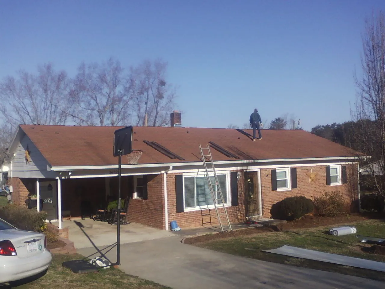 Roofer stripping a shingle roof on a brick ranch before metal panels in Rockbridge