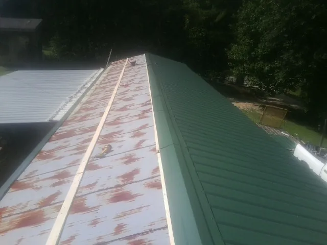 Old rusted panels beside newly installed green metal roofing — Wind Damage Roof Repair by Roofing Brothers in Rockbridge