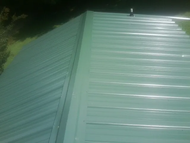 New green metal panels meeting at the ridge of a roof — Flat Roof Repair work by our crew in Rockbridge