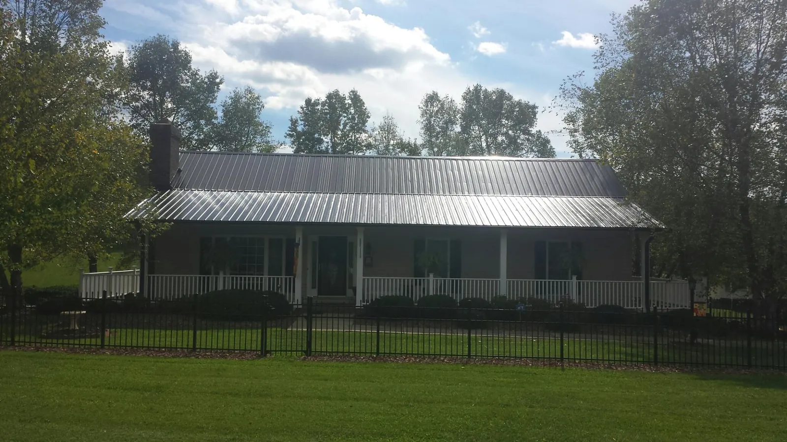 Gray metal roof on a brick ranch with a full width front porch — Gutter Guard Installation work by our crew in Rockbridge