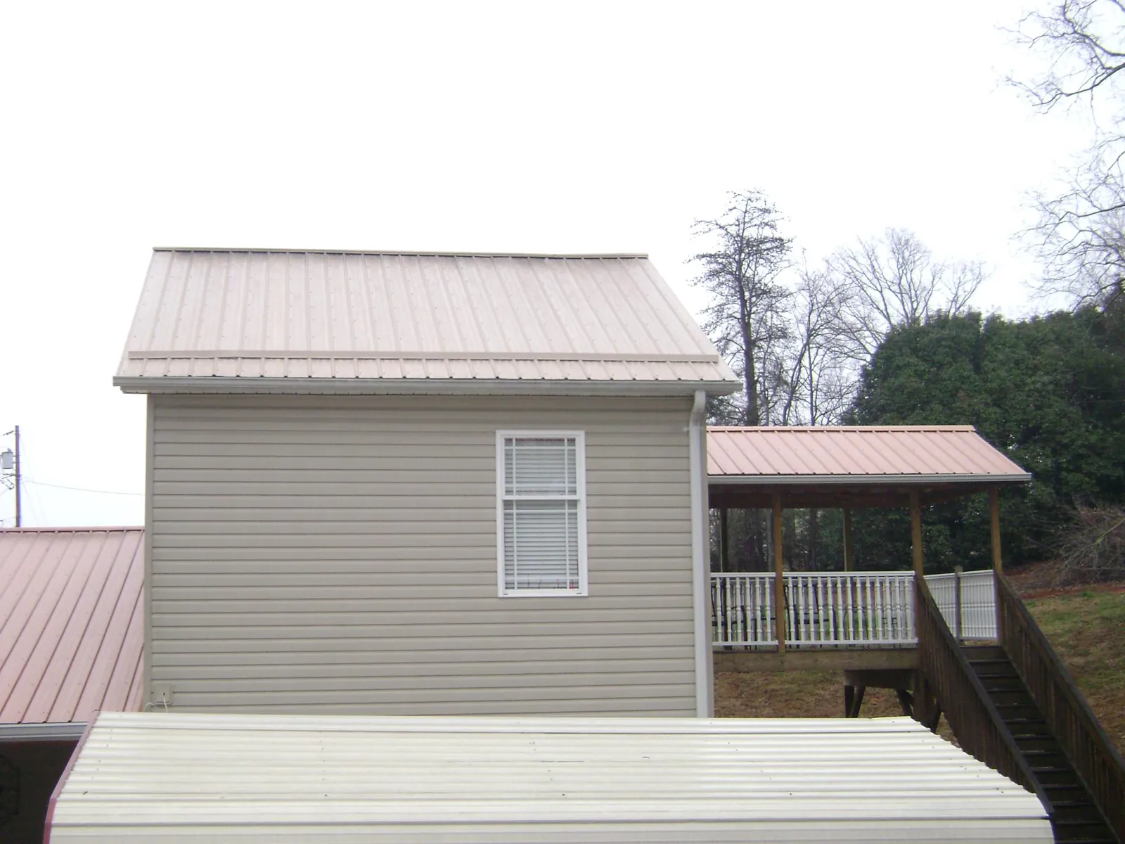 Tan metal roofs on a two story addition and attached porch, from a Roof Replacement job in Rockbridge