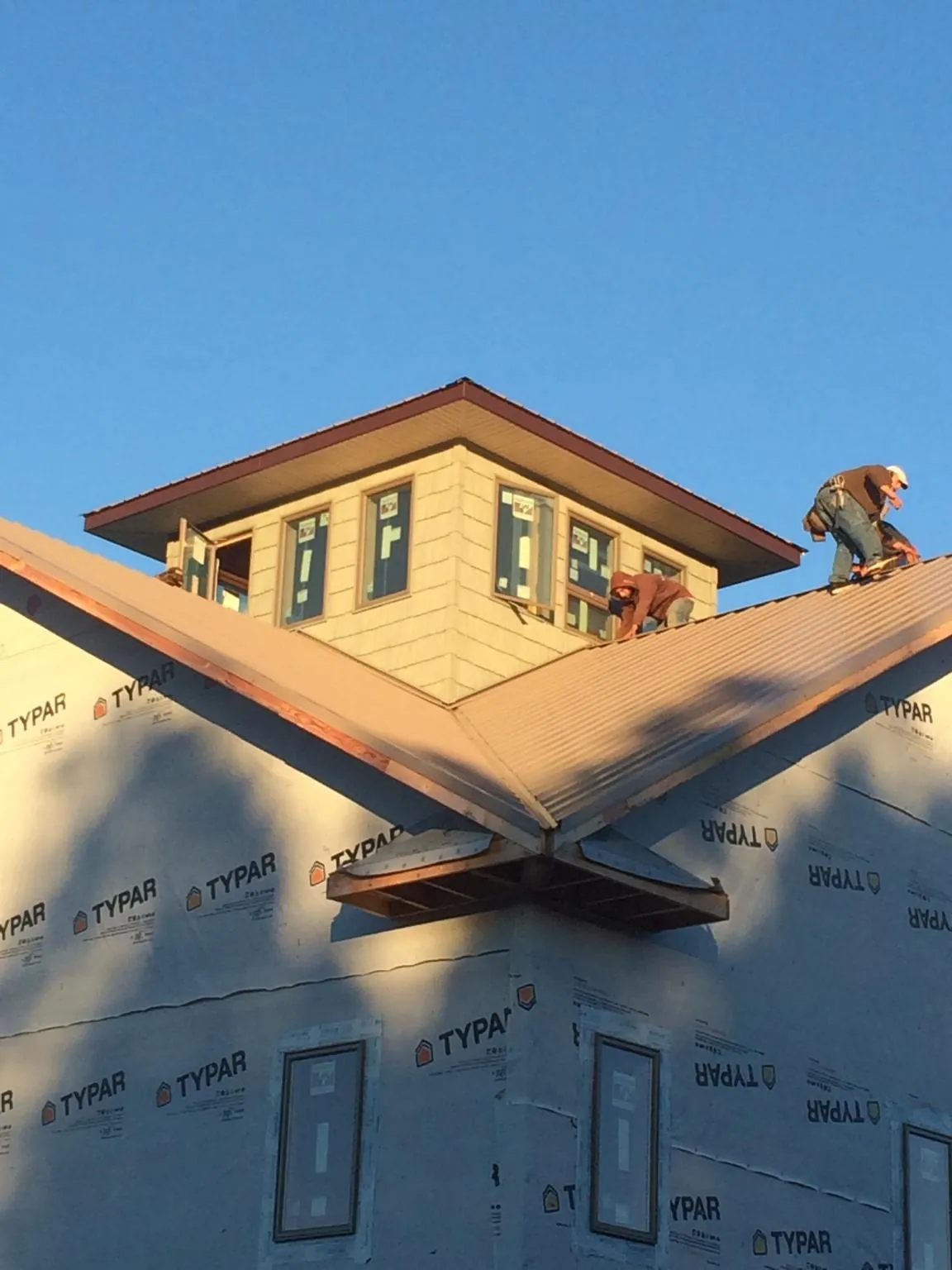 Roofers working around a rooftop cupola on a new metal roof at sunset — Roof Waterproofing in Rockbridge by Roofing Brothers